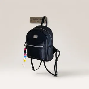 Gros plan du sac à dos en cuir noir avec zips argentés et breloque en perles colorées
