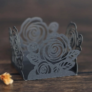 Détail de caissettes en papier noir découpé au laser avec motifs de roses délicats