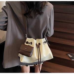 Detail of cream drawstring bucket bag with brown leather straps shown on a model