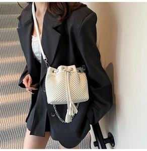 Quilted white bucket bag detail showing drawstring closure and silver chain with tassels