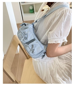 Détail du sac à épaule bleu clair en cuir verni avec nœuds et bandoulière réglable