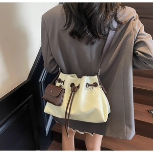 Detail view of cream drawstring bucket bag with mini brown pouch and slim shoulder strap