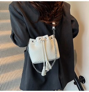 Close-up of white drawstring bucket bag featuring quilted texture and stylish tassel detail
