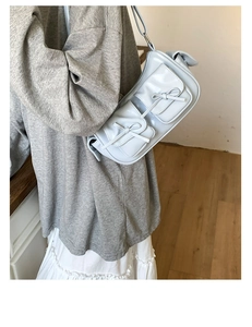 Détail du sac bleu clair avec deux poches à nœuds et finitions métalliques argentées