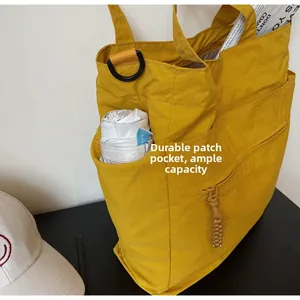 Detail of yellow nylon tote bag side pocket for umbrellas with durable fabric texture