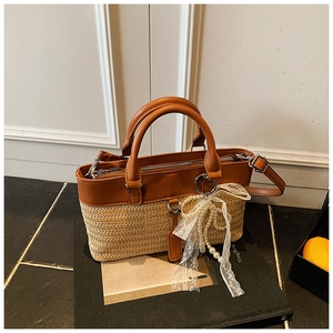 Detail of straw handbag with brown leather trim, white lace bow, and pearl chain charm