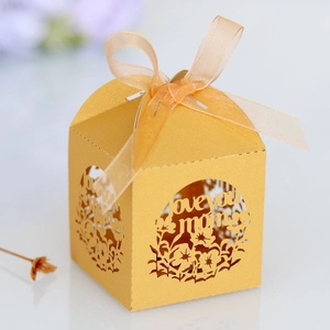 Détail boîte cadeau dorée découpée au laser avec texte 'love you mom' et ruban