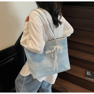 Dettaglio della borsa tote azzurra glitterata con fiocco in pizzo bianco e perle