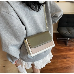Detail of tricolor crossbody bag with gold chain strap on olive and pink matte faux leather