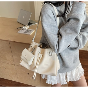 Chic cream shoulder bag with mini pouch on a wooden desk with laptop and headphones