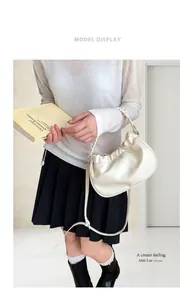 Detail of creamy ruched cloud bag showing soft faux leather and woven shoulder strap
