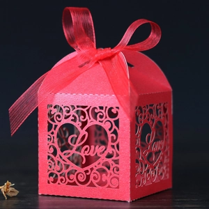 Detail of red laser-cut wedding candy box with Love heart pattern and satin ribbon bow