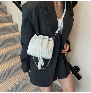 Detail of white bucket bag with woven texture, drawstring closure and silver chain