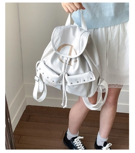 Détail du sac à dos blanc avec logo D artistique marron et rivets métalliques argentés