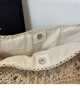 Macro detail of beige straw tote bag with magnetic snap closure and linen lining