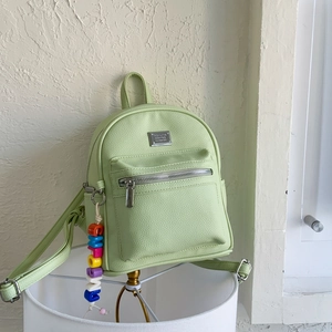Vue détaillée d'un mini sac à dos vert clair avec zip argenté et pendentif en perles
