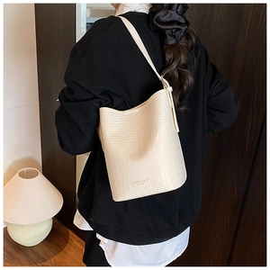Close-up of cream bucket bag showing crocodile embossed texture and printed fashion logo