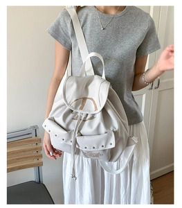 Détail du sac à dos crème avec fermeture à cordon, rivets en métal et poches imprimées