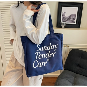 Dettaglio della borsa tote in tela blu scuro con scritte bianche in una scena di vita