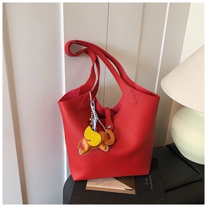Detail of red lychee grain leather tote bag with a colorful elephant leather charm accessory