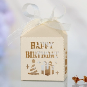 Detail of cream laser-cut Happy Birthday candy box with white ribbon and hollow patterns