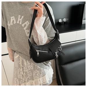 Close-up of black lychee grain leather shoulder bag with metallic zipper and biker style details