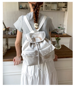 Vue détaillée du dos d'un sac à dos blanc de style collège avec cordon et clous