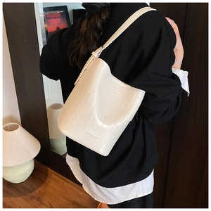 Detail of white crocodile pattern bucket bag with adjustable strap and embossed text