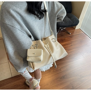 Detail view of cream drawstring bucket bag with matching pouch and silver ring hardware
