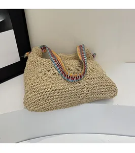Macro shot of bohemian woven straw tote bag with colorful ethnic style shoulder strap