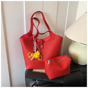 Detail of red pebbled leather tote bag with small pouch and cute elephant charm