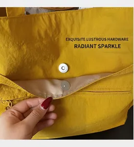Close-up of magnetic snap closure and inner zipper pocket on yellow nylon tote bag