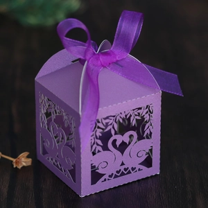 Close-up of laser-cut purple swan heart candy box with silk ribbon on wood background