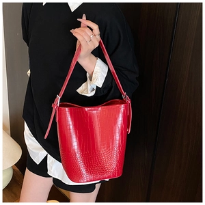 Detail shot of a vibrant red crocodile pattern bucket bag with shiny PU leather texture