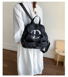 Gros plan du sac à dos en nylon noir avec logo D blanc et poches à rivets argentés