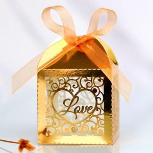 Detailed laser-cut golden Love heart wedding favor box with orange organza ribbon bow