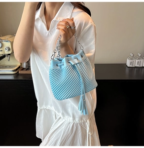 Detail view of light blue bucket bag with diamond texture and silver chain strap