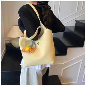 Detail of creamy yellow pebble leather tote bag with a cute elephant charm accessory