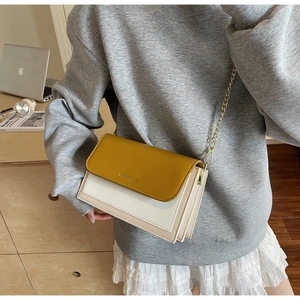 Detail of vintage bicolor crossbody bag with mustard yellow flap and chain strap