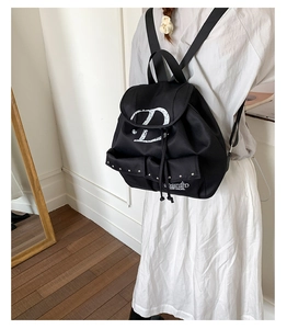 Détail du sac à dos en nylon noir avec lettre D artistique et rivets décoratifs argentés