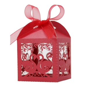 Close-up of red laser-cut swan heart wedding favor box with a translucent organza ribbon
