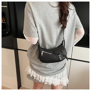 Detail of black lychee grain leather saddle bag with silver zippers and metal rings