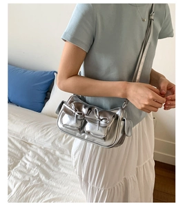Détail du sac à bandoulière argenté métallisé avec nœuds décoratifs et plusieurs poches