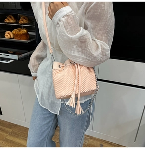 Close-up of pink woven bucket bag featuring drawstring closure and tassel details