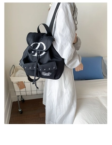 Détail d'un sac à dos en nylon noir avec des rivets en métal argenté et imprimé graphique