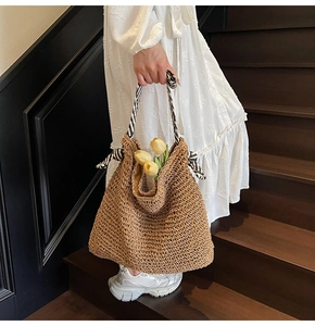 Detailed texture of hand-woven straw tote bag with black and white striped ribbon handle
