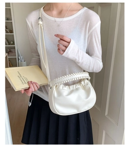 Detail of white pleated moon bag featuring woven handle and soft faux leather texture