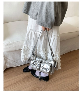 Détails d'un sac à bandoulière argenté avec deux poches avant et décor de nœuds
