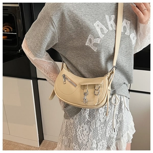 Close-up of beige litchi grain leather saddle bag on shoulder with silver hardware