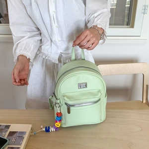 Détail du sac à dos vert menthe en similicuir avec logo argenté et breloques colorées